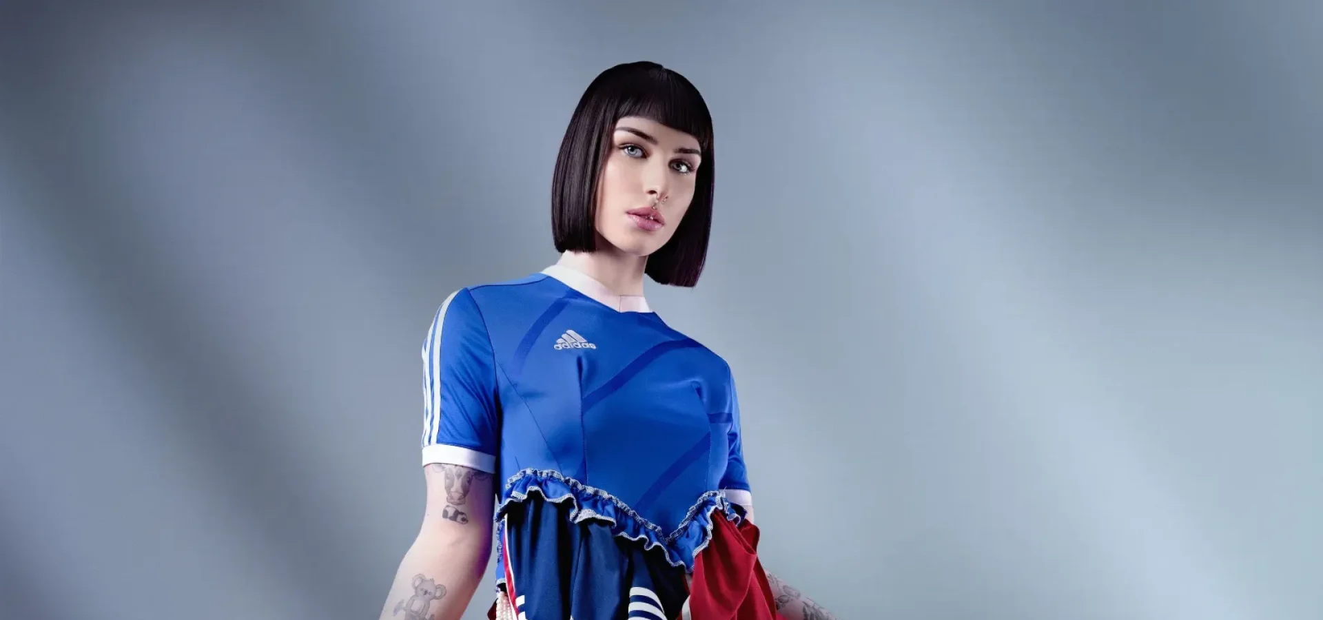 Fashion portrait featuring a sleek black bob haircut paired with a layered sports-inspired editorial outfit.