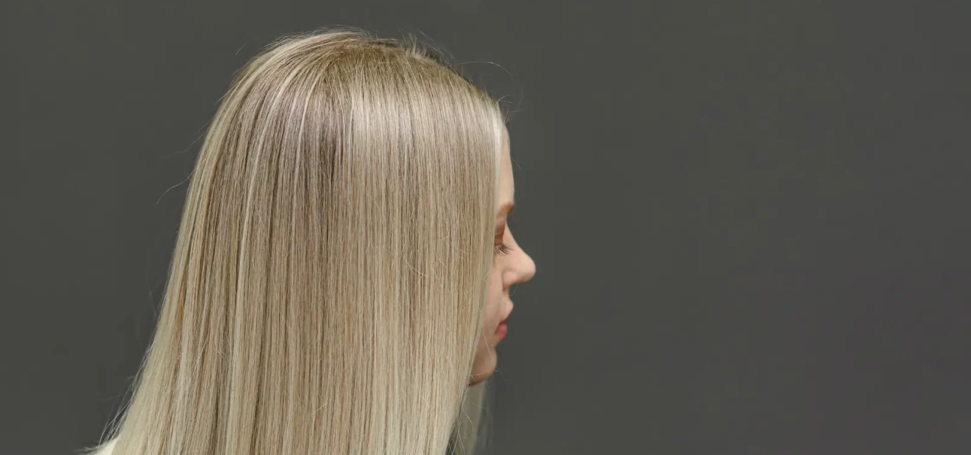Woman with short blonde straight hair wearing a black blouse faces to the side.