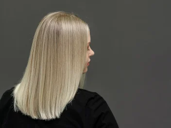 Woman with short blonde straight hair wearing a black blouse faces to the side.