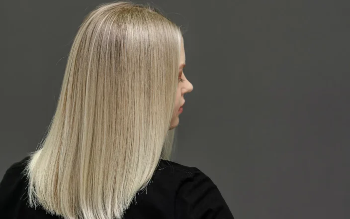 Woman with short blonde straight hair wearing a black blouse faces to the side.