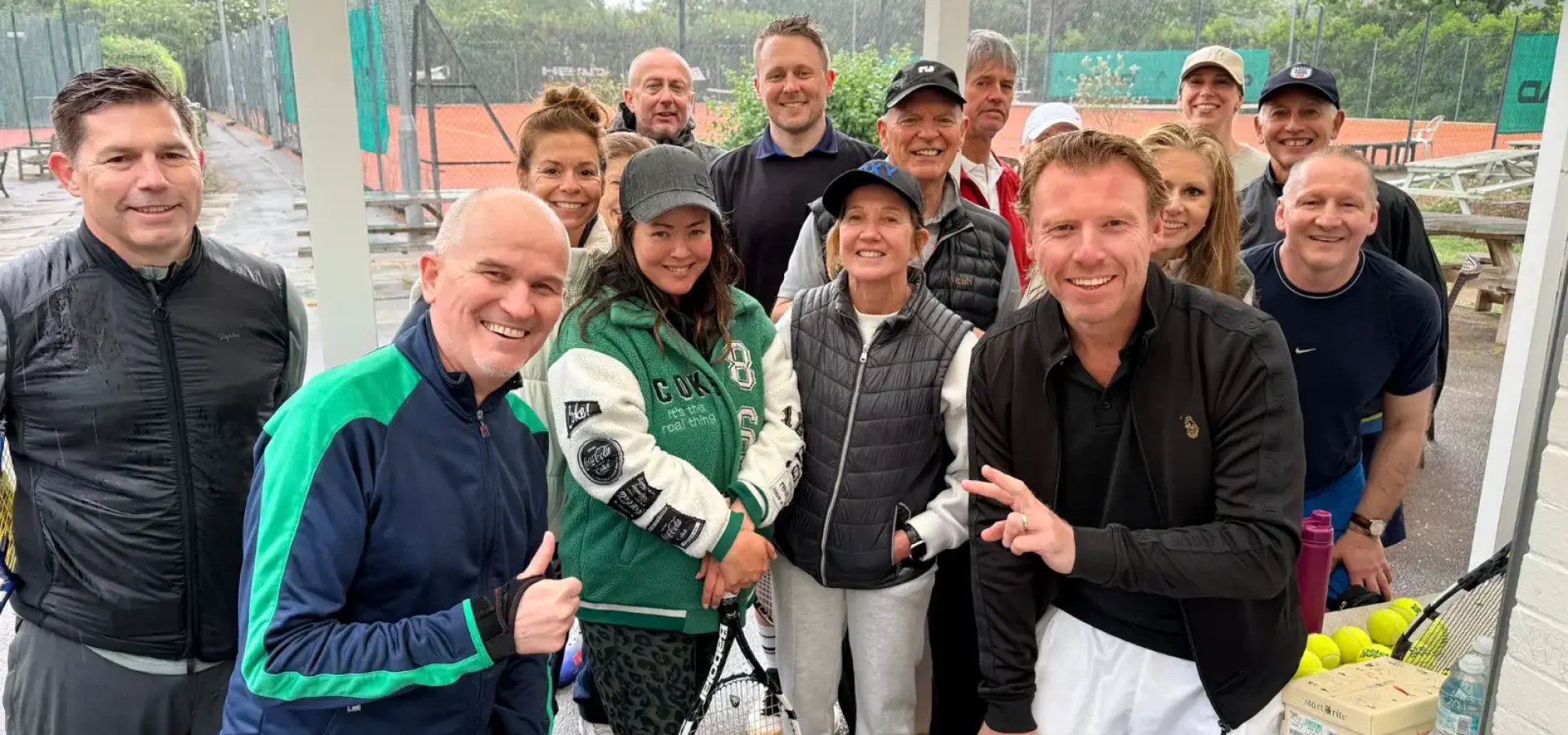 Group of tennis players and Hair & Beauty Charity supporters posing courtside during a charity fundraising tournament.