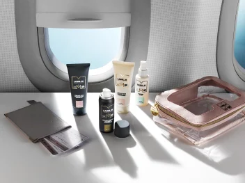 LABEL.M mini haircare collection displayed with travel essentials beside an airplane window.