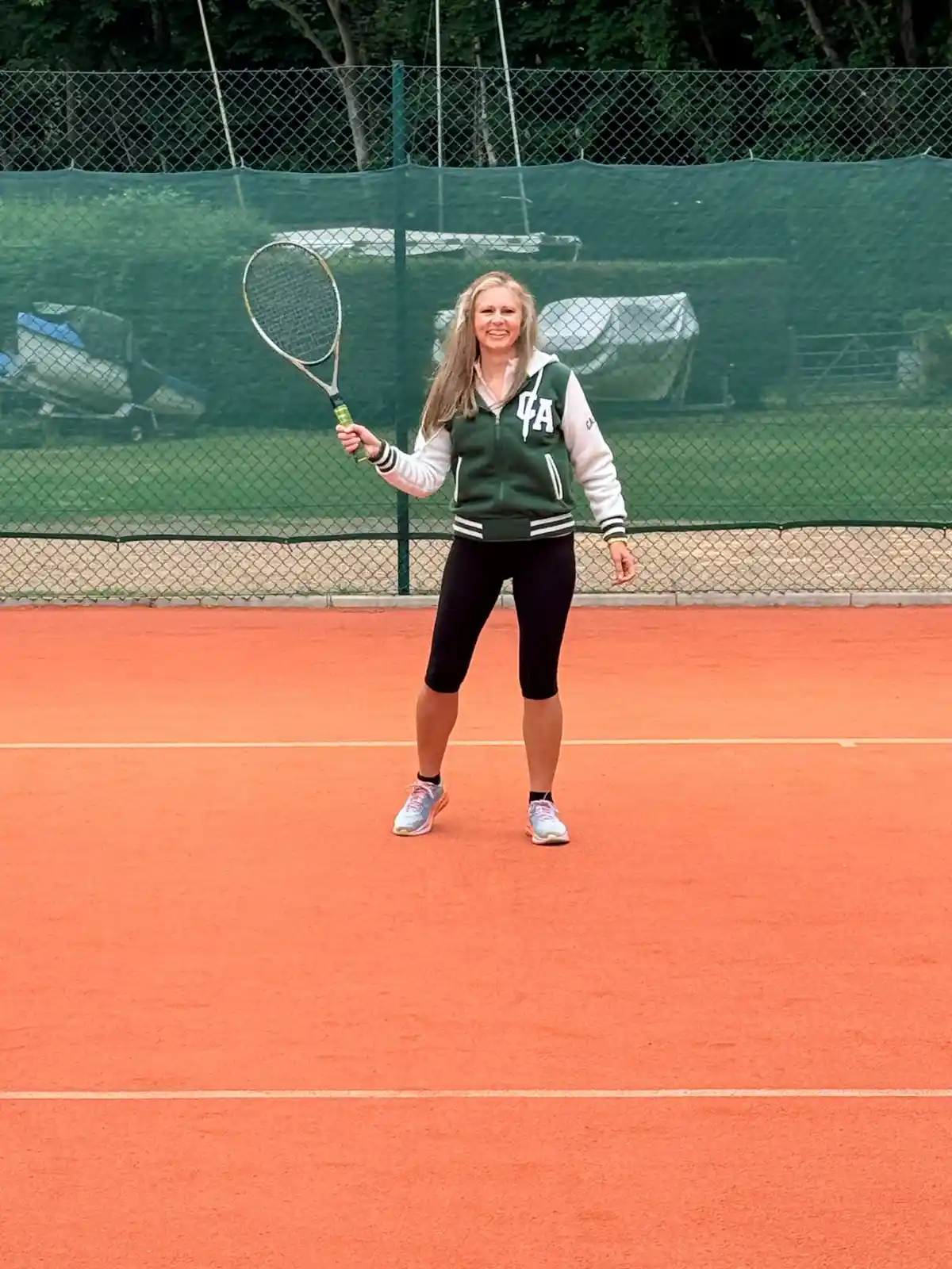 Woman holding a tennis racket on a clay court during a Hair & Beauty Charity tennis fundraising event.