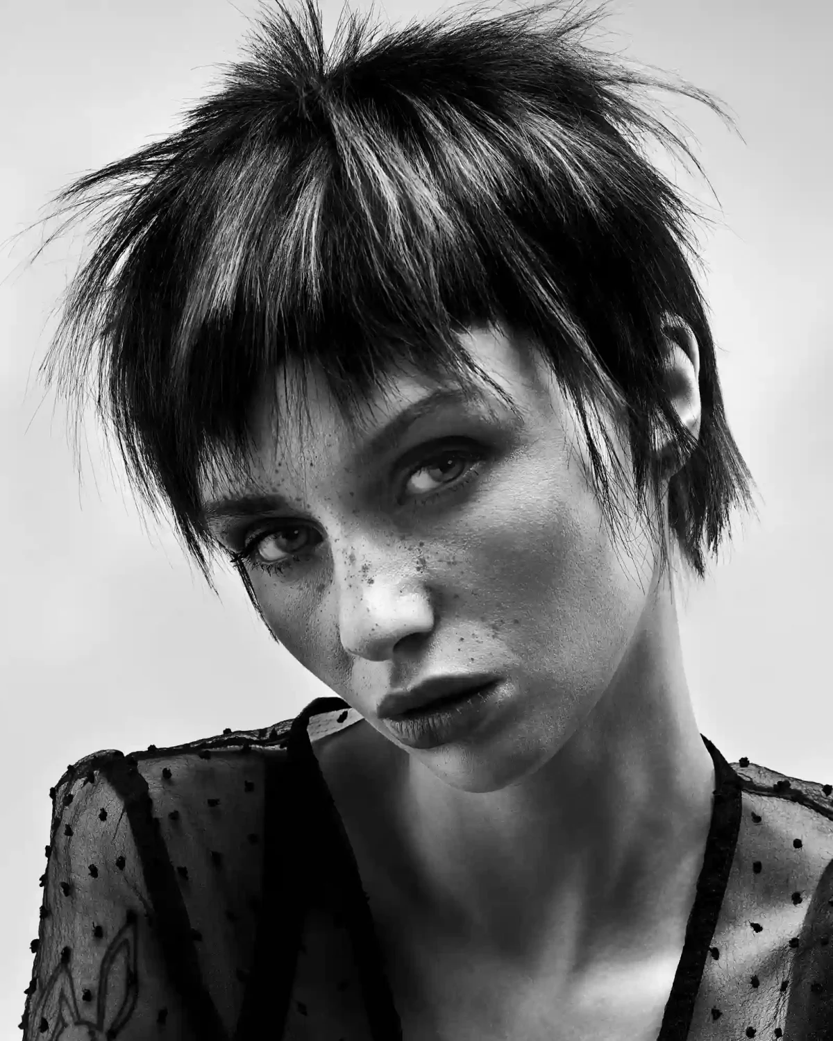 Black-and-white editorial pixie cut with textured layers, wispy fringe and sharp detailing for a modern avant-garde look.