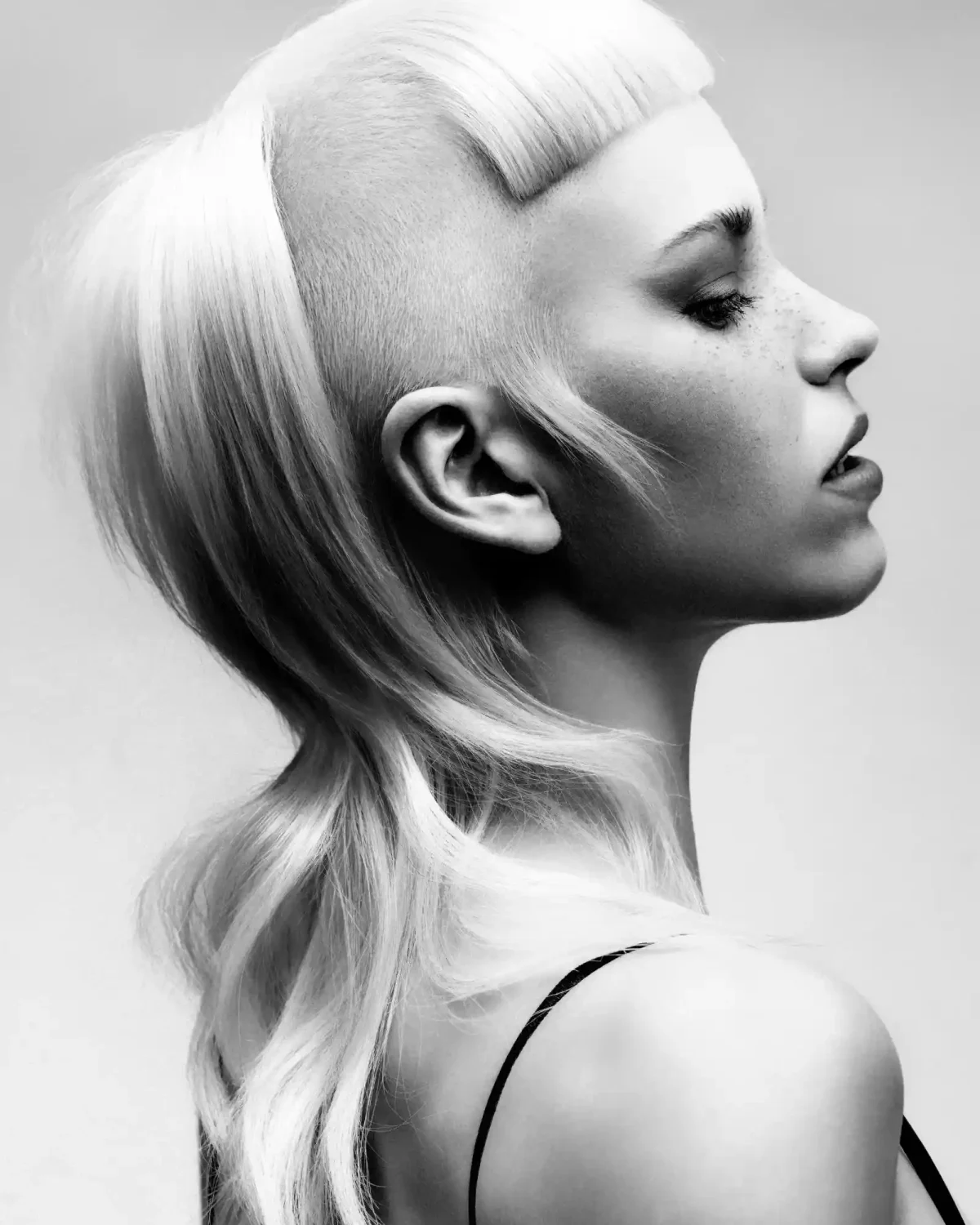 Black-and-white editorial hairstyle featuring shaved sides, sculpted fringe and soft flowing lengths at the back.