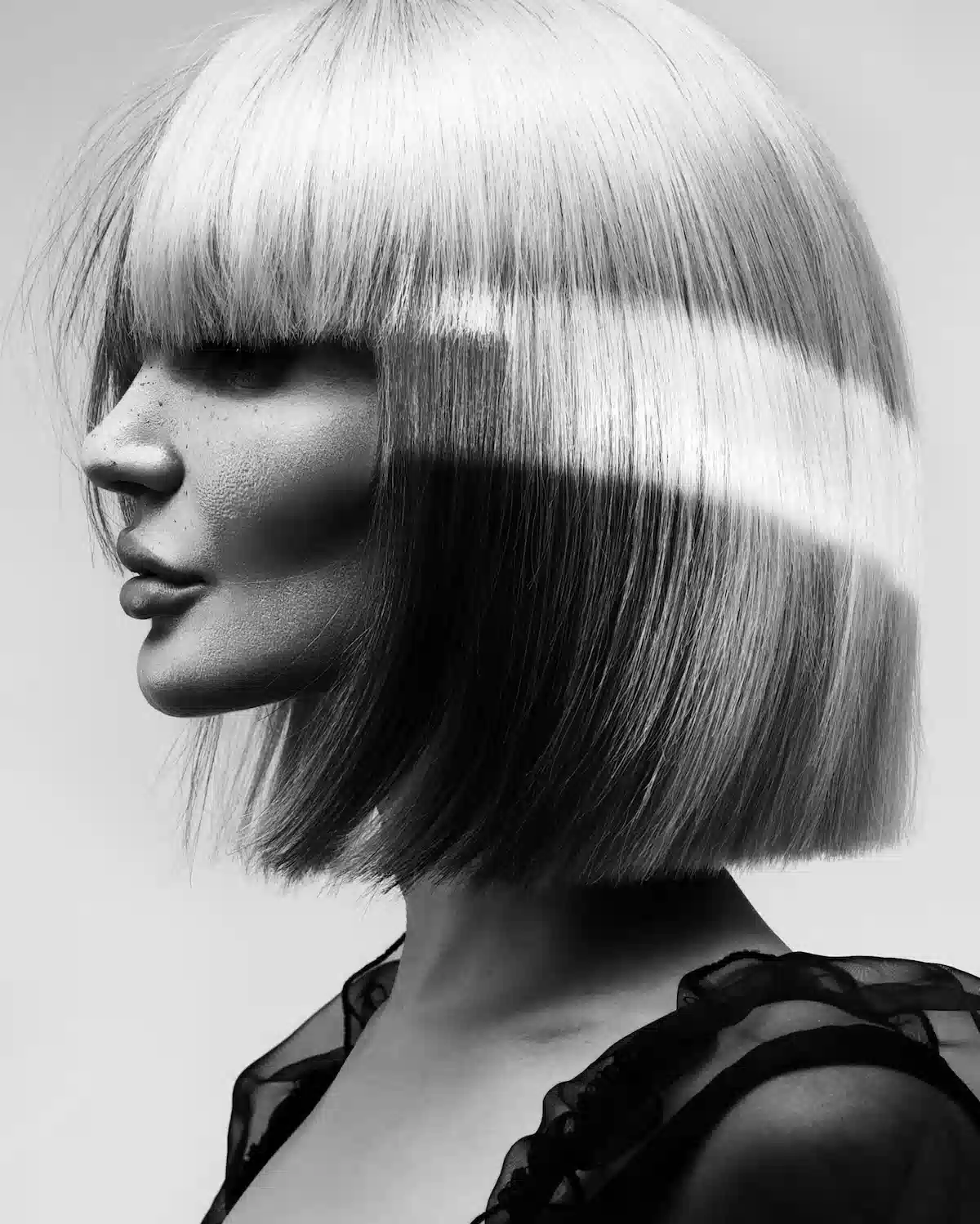Black-and-white editorial bob with blunt fringe and contrasting colour panels, styled with sleek precision and shine.