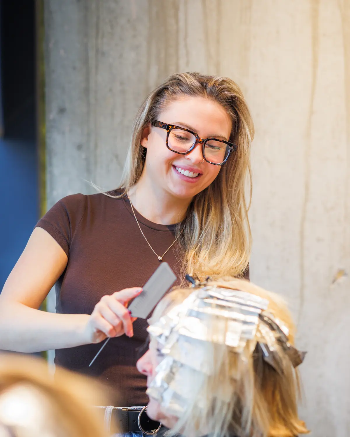 Hair extension specialist fitting blonde extensions during a salon appointment.