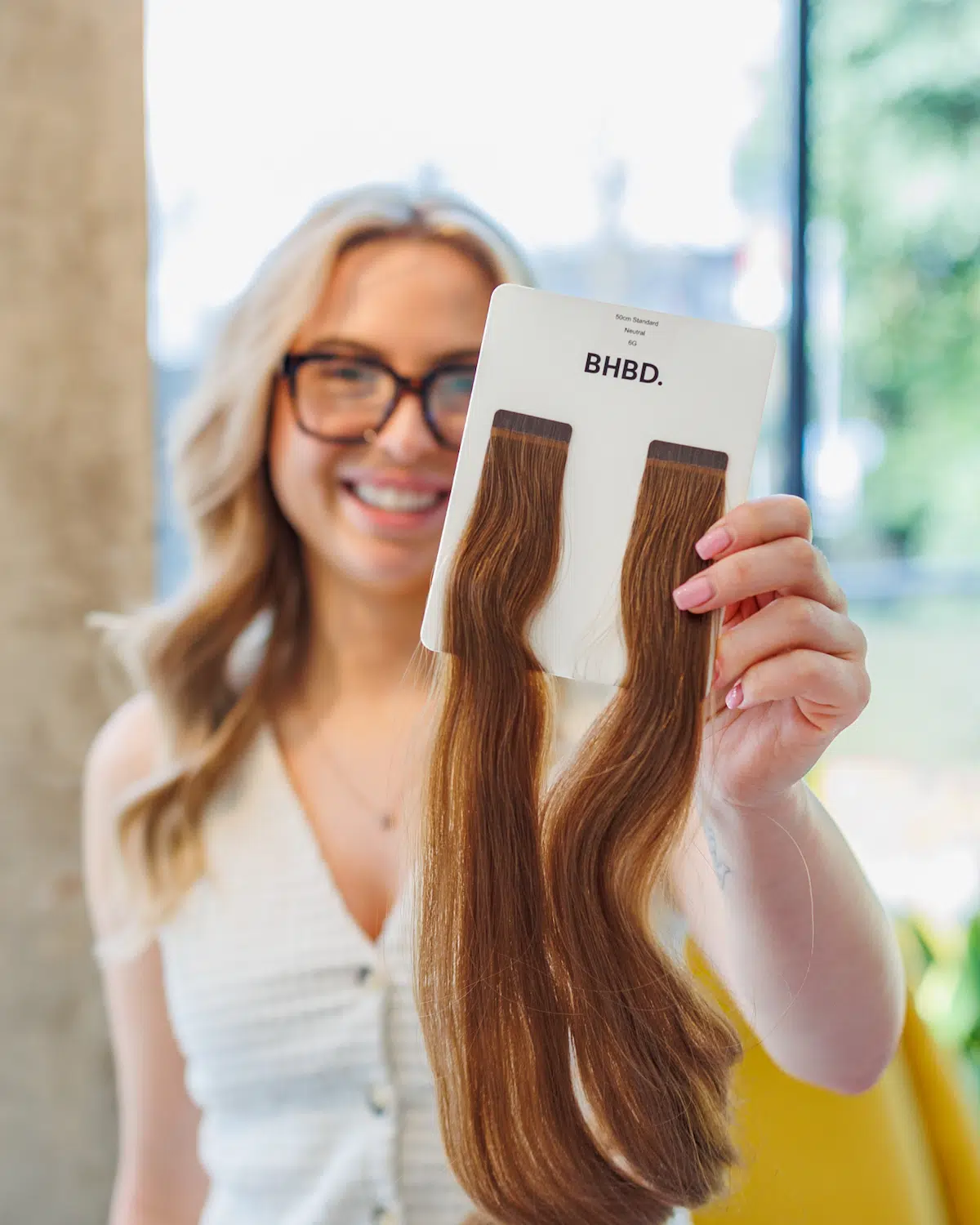 Hair extension specialist holds two brown hair extensions.