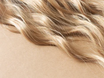 Close-up of glossy blonde beach waves with warm honey tones and soft texture, showcasing healthy, dimensional hair colour.