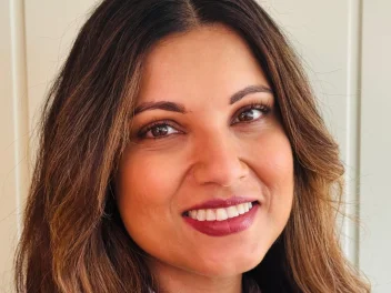 Portrait of Alex Thaddeus, beauty industry professional, smiling with soft waves and natural makeup in a professional headshot.