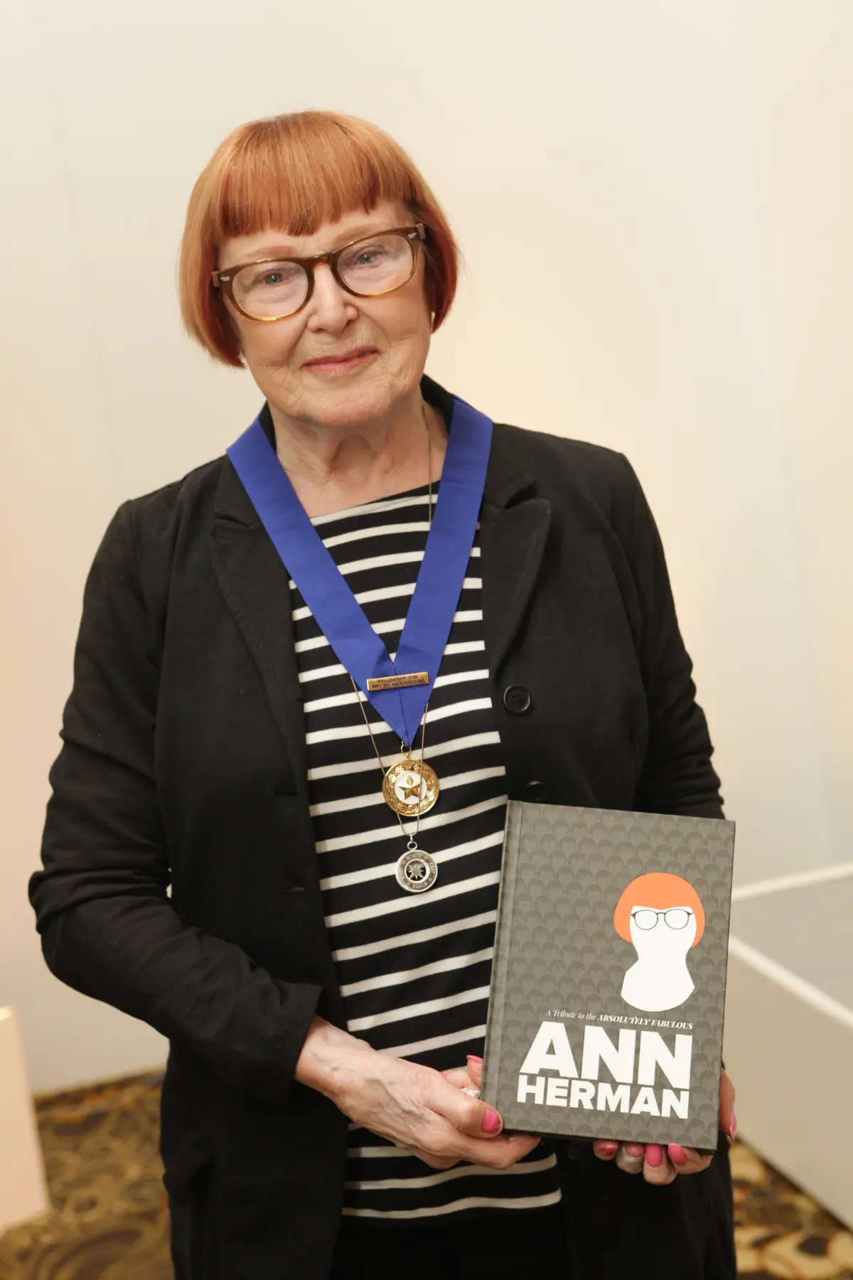 Women in a stripey top holding the Ann Herman book.