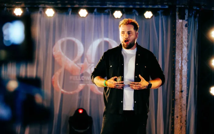 Jordan Heyes speaks on stage at an event.