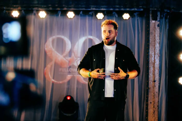 Jordan Heyes speaks on stage at an event.