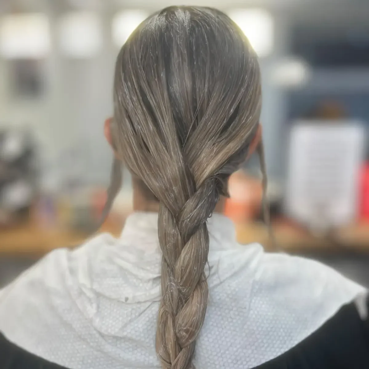Client with neatly braided hair wrapped in a disposable salon towel, showcasing a clean, comfortable and hygienic professional hair service.