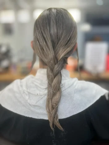 Client with neatly braided hair wrapped in a disposable salon towel, showcasing a clean, comfortable and hygienic professional hair service.