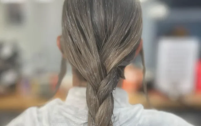 Client with neatly braided hair wrapped in a disposable salon towel, showcasing a clean, comfortable and hygienic professional hair service.