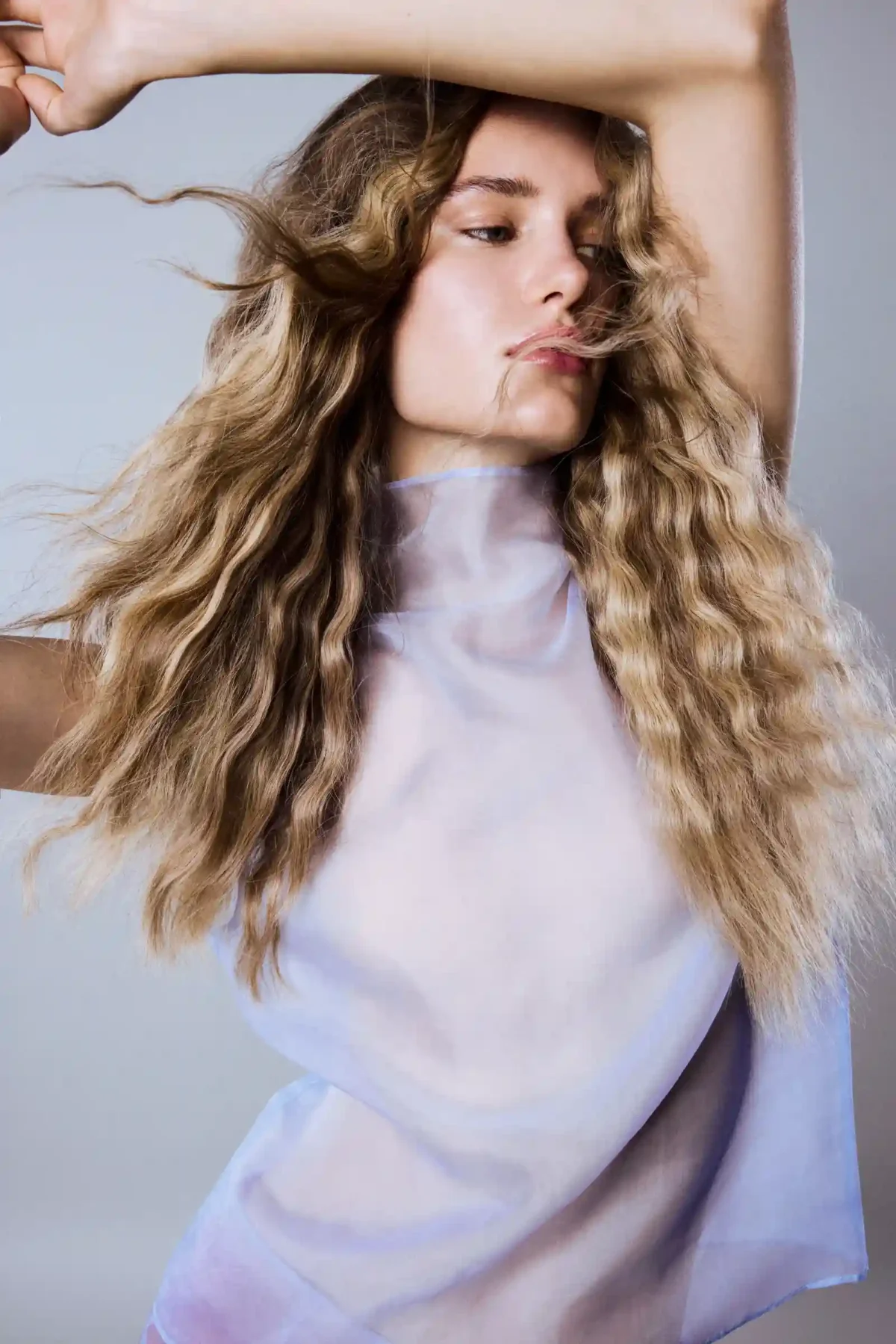 Model with textured beach waves and dimensional blonde hair, showcasing soft summer volume, movement and healthy shine.