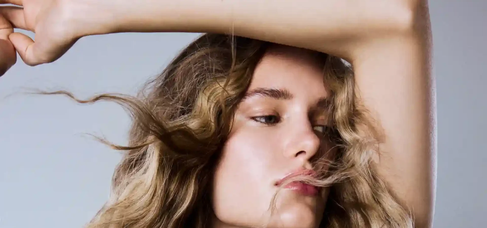 Model with textured beach waves and dimensional blonde hair, showcasing soft summer volume, movement and healthy shine.