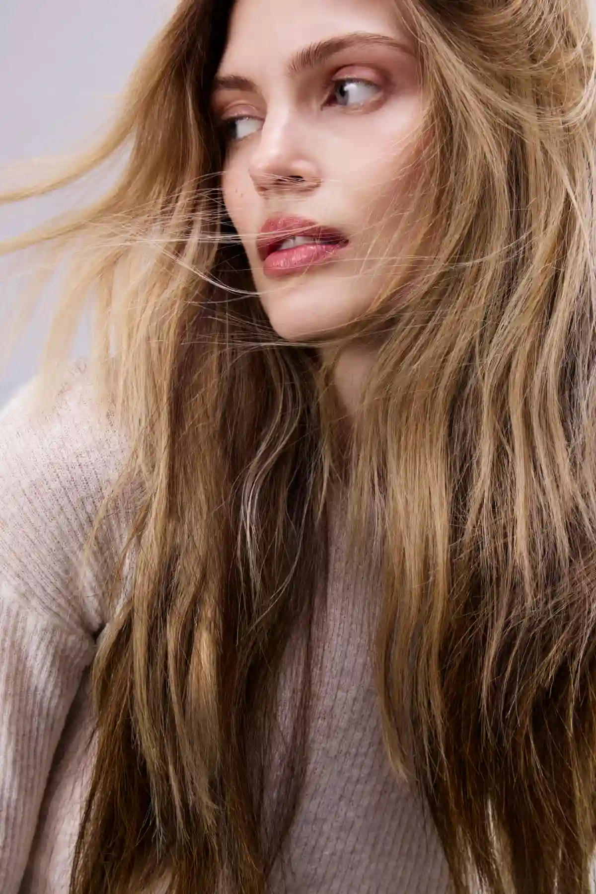 Model with long lived-in blonde balayage hair featuring soft caramel dimension and natural summer texture.