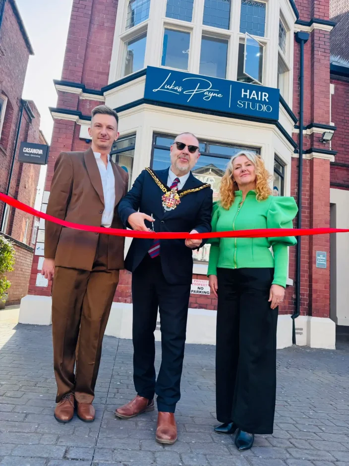 Salon members stand beside the Major as the opening rope its cut to the new salon.