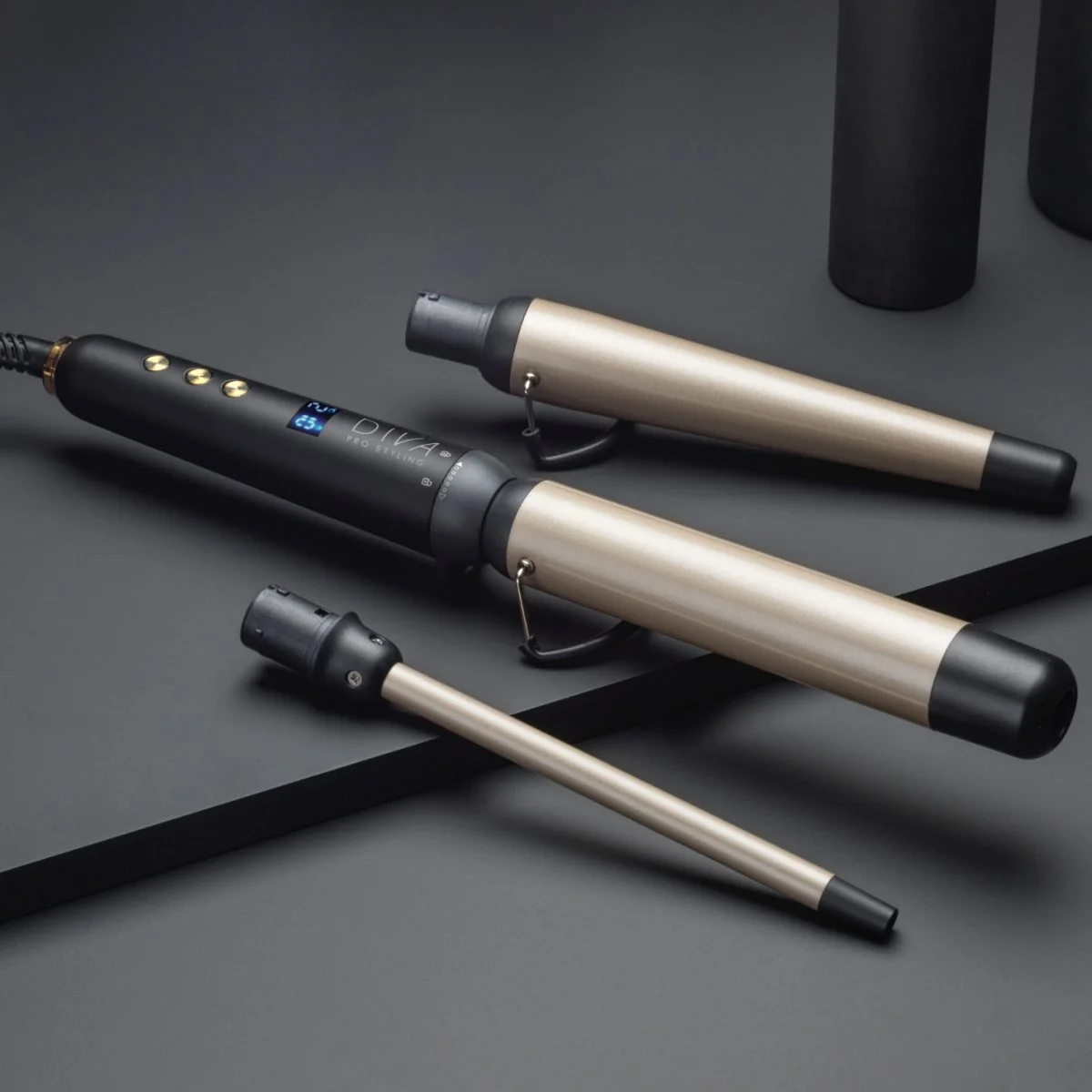 ghd Multi Wand with 2 replaceable head attachments sit on a a black surface.