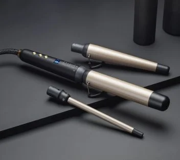 ghd Multi Wand with 2 replaceable head attachments sit on a a black surface.