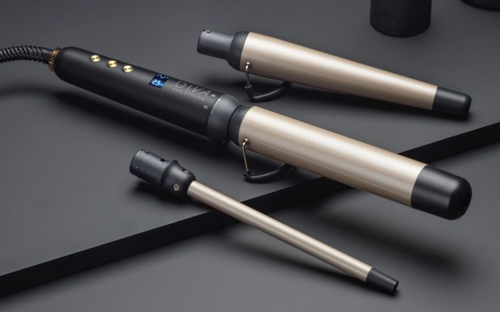 ghd Multi Wand with 2 replaceable head attachments sit on a a black surface.