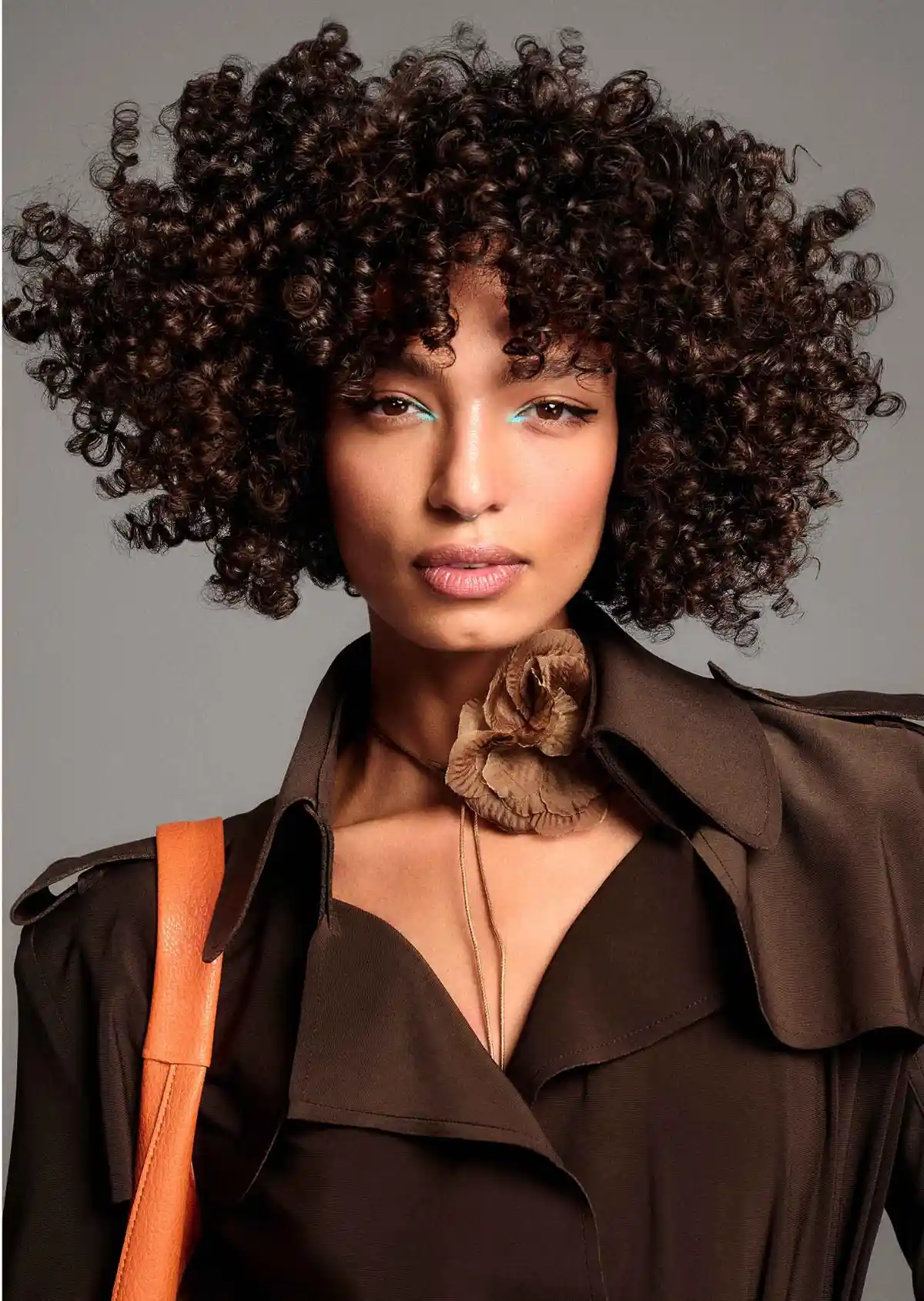 Model with defined dark brunette curls showcasing the TONI&GUY 2026 collection with glossy, voluminous textured hair.