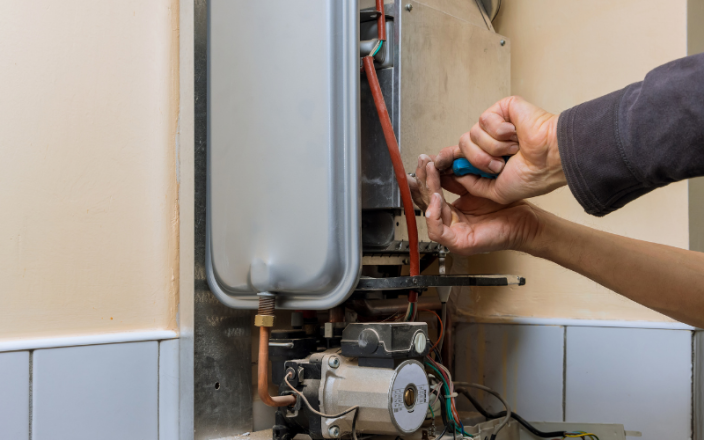 Hands fixing a boiler to highlight Alex Thaddeus's article on life lessons.