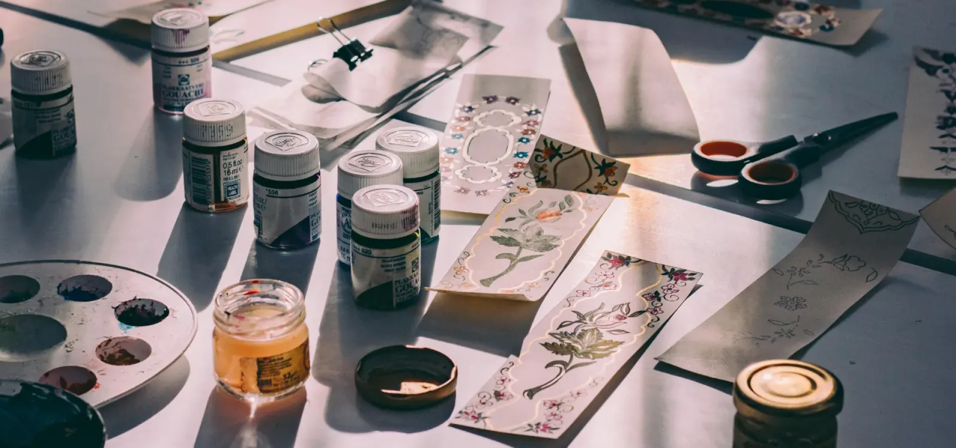 A table filled with creative tools featuring paint and brushes.