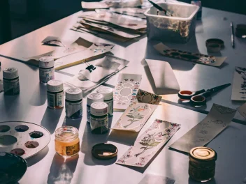 A table filled with creative tools featuring paint and brushes.