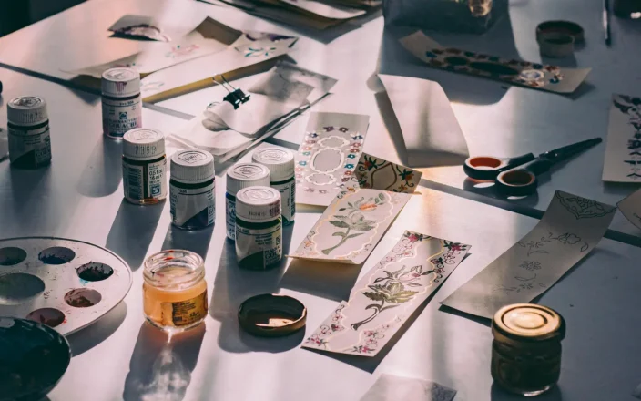A table filled with creative tools featuring paint and brushes.