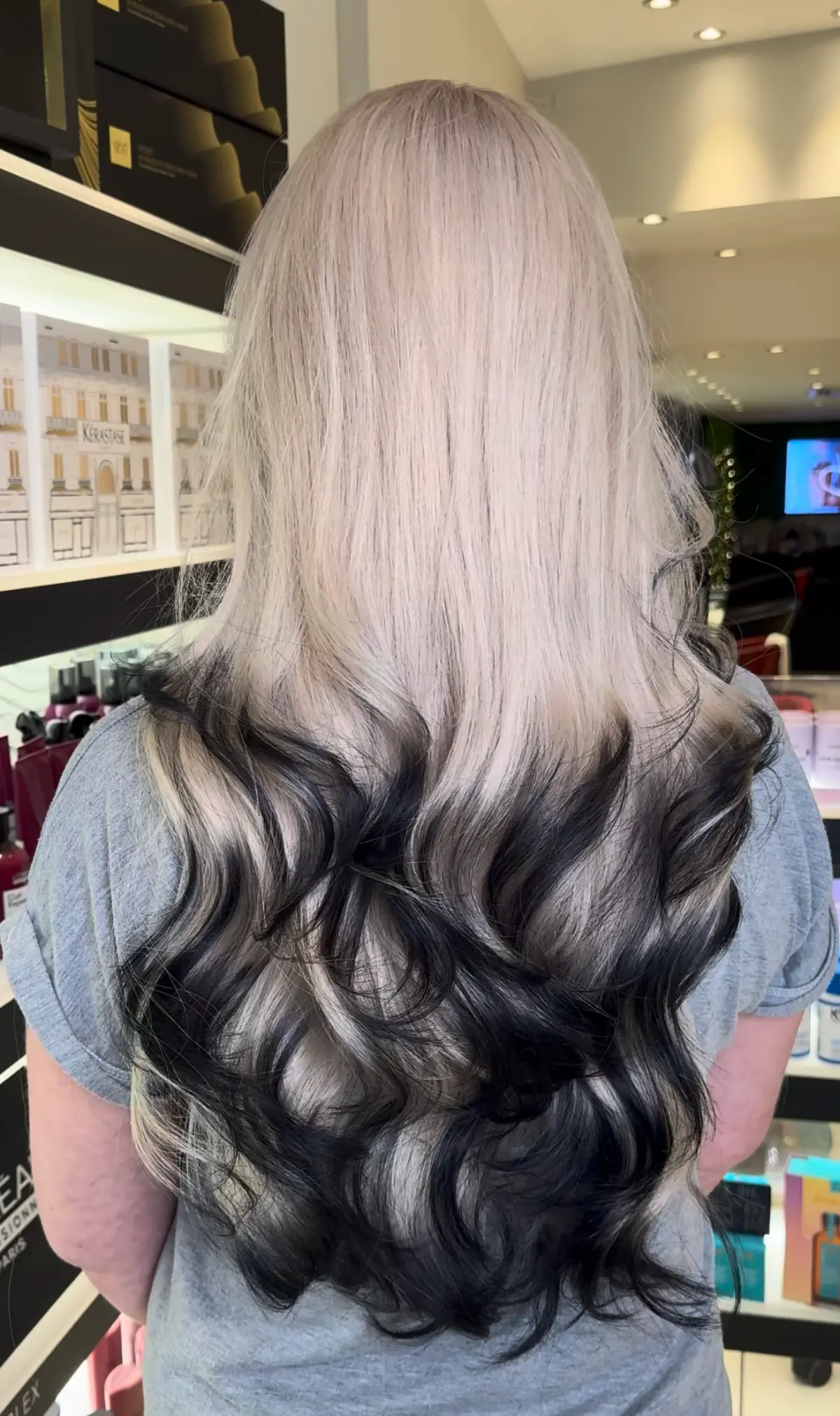 Model faces away from the camera showing her fox tips hair trend with blonde roots and black tips.