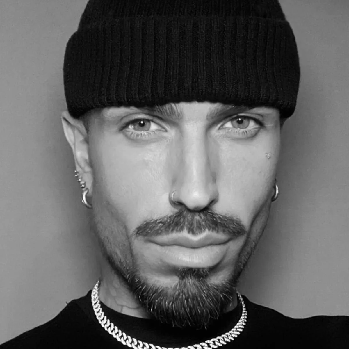 Portrait of celebrity hairstylist Harold Casey wearing a black beanie, hoop earrings and chain necklace.