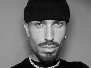 Portrait of celebrity hairstylist Harold Casey wearing a black beanie, hoop earrings and chain necklace.