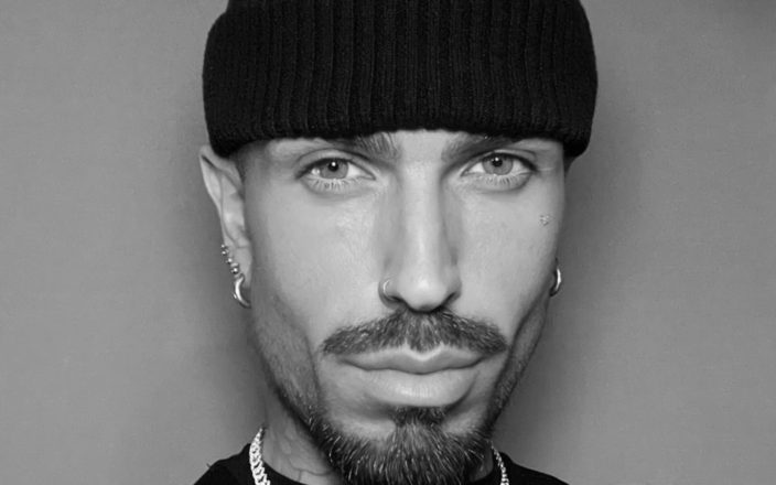 Portrait of celebrity hairstylist Harold Casey wearing a black beanie, hoop earrings and chain necklace.