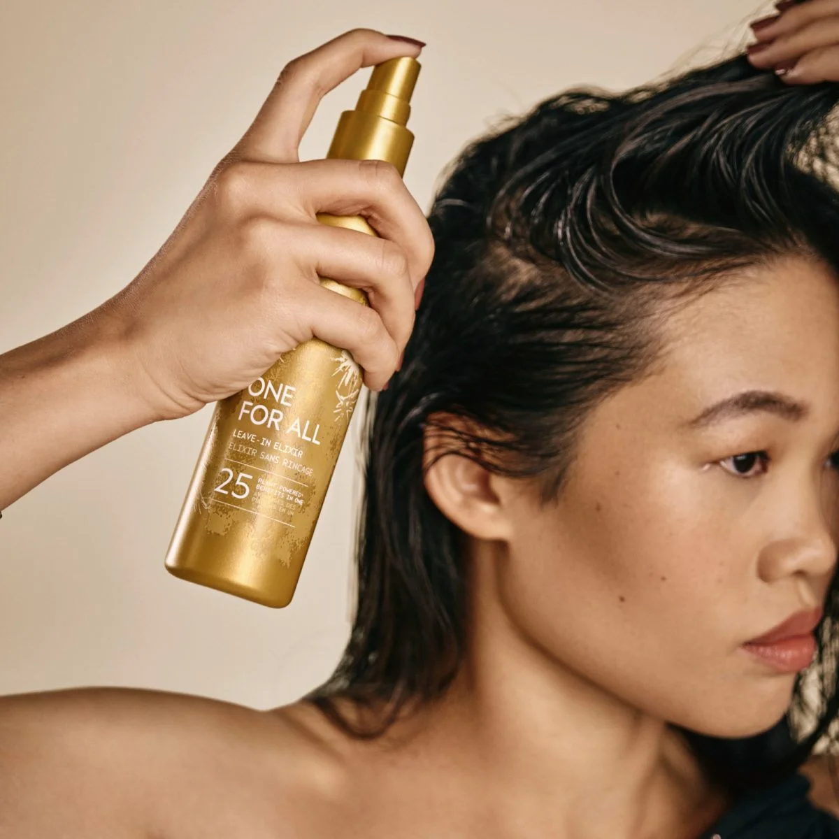 A Model dprays Aveda One for All Leave In Elixir onto her hair.