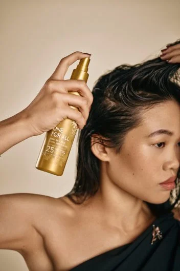 A Model dprays Aveda One for All Leave In Elixir onto her hair.