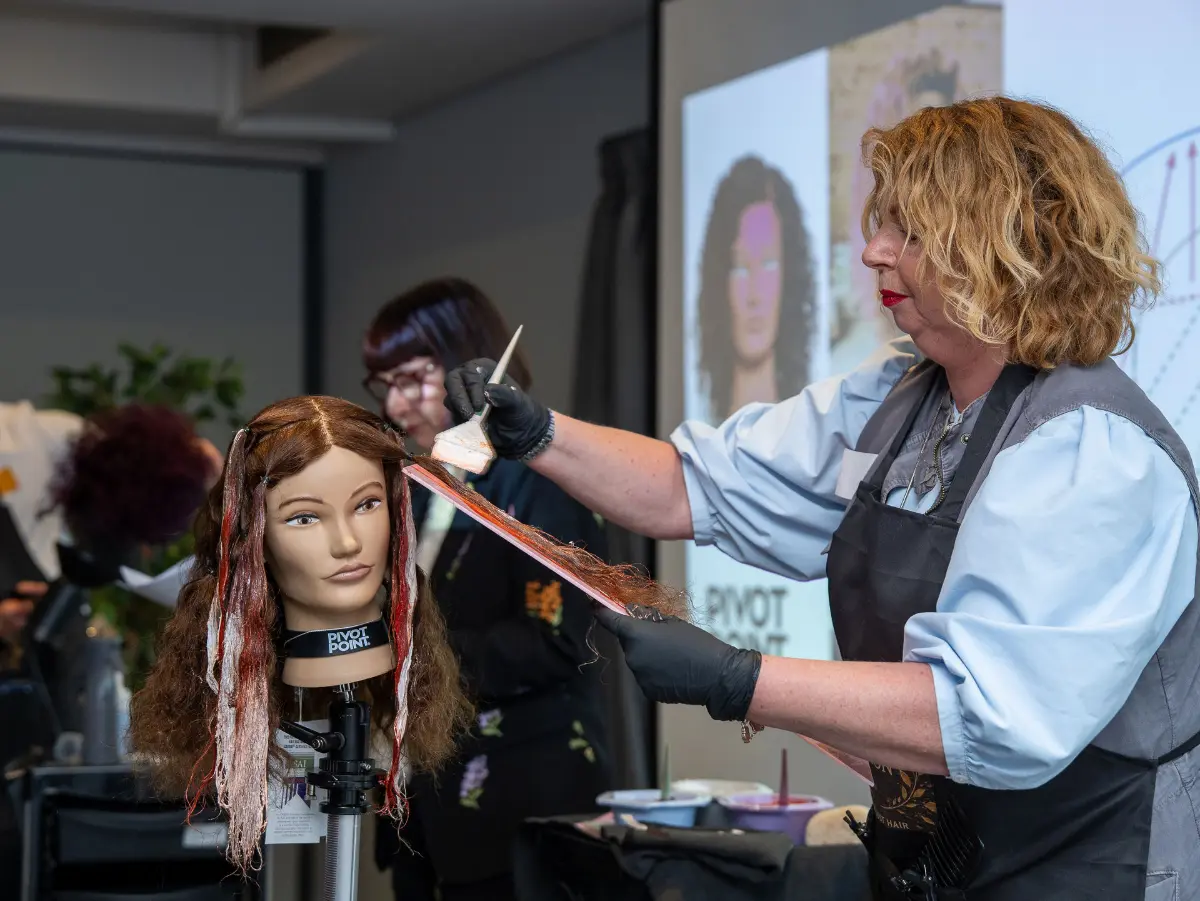 Hairdresser does highlights on a mannequin head during a demo at Never Just Hair exhibition.