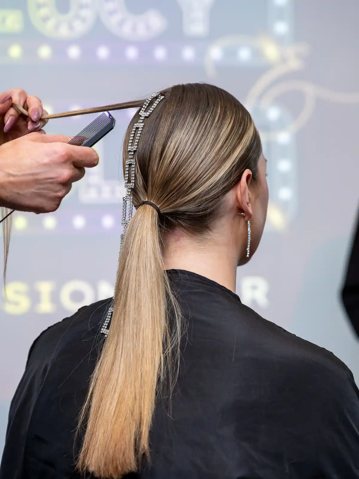 Model with long blonde hair has a chain hair accessory fitted at Never Just Hair exhibition.