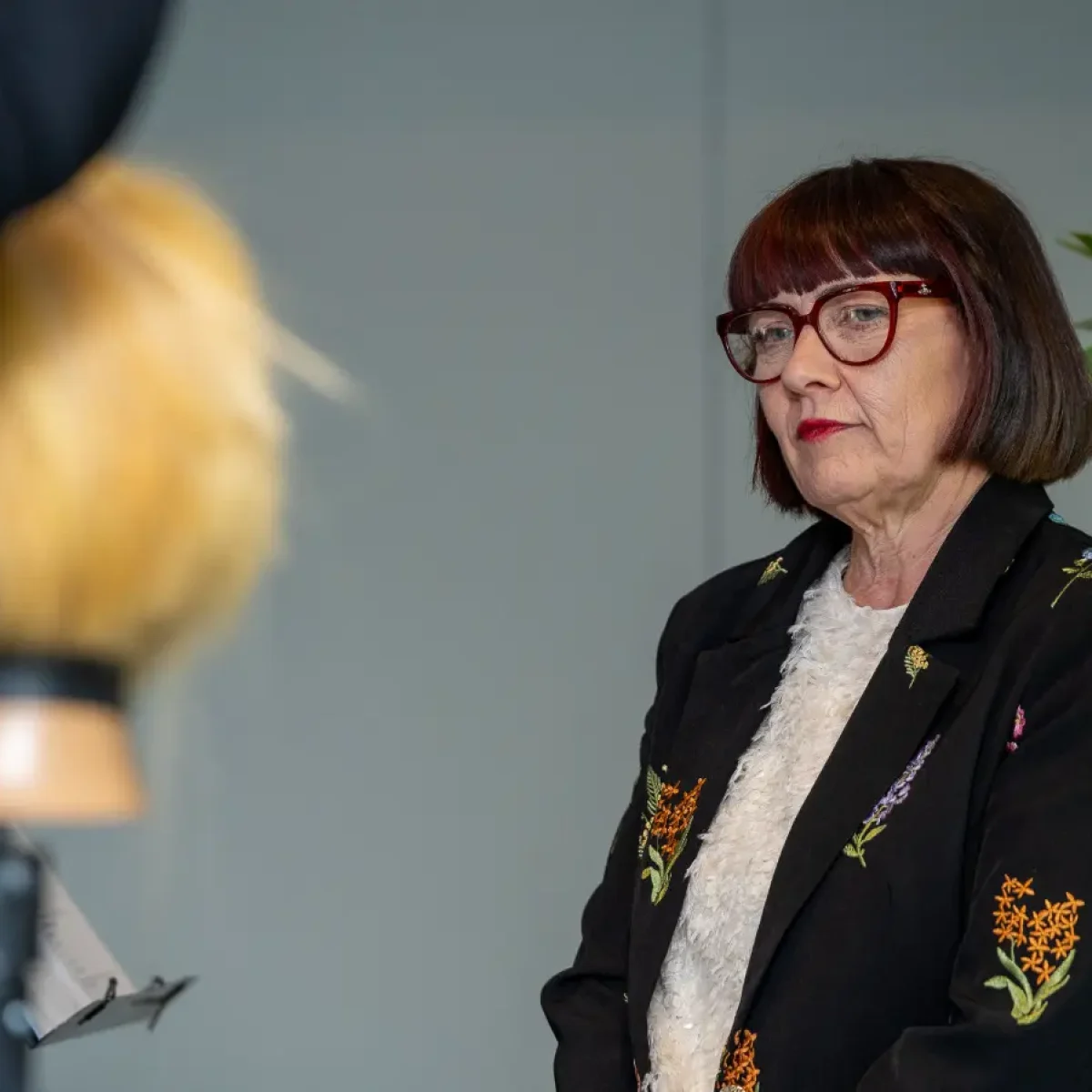 Woman with short brown hair watches a demo at Never Just Hair exhibition.
