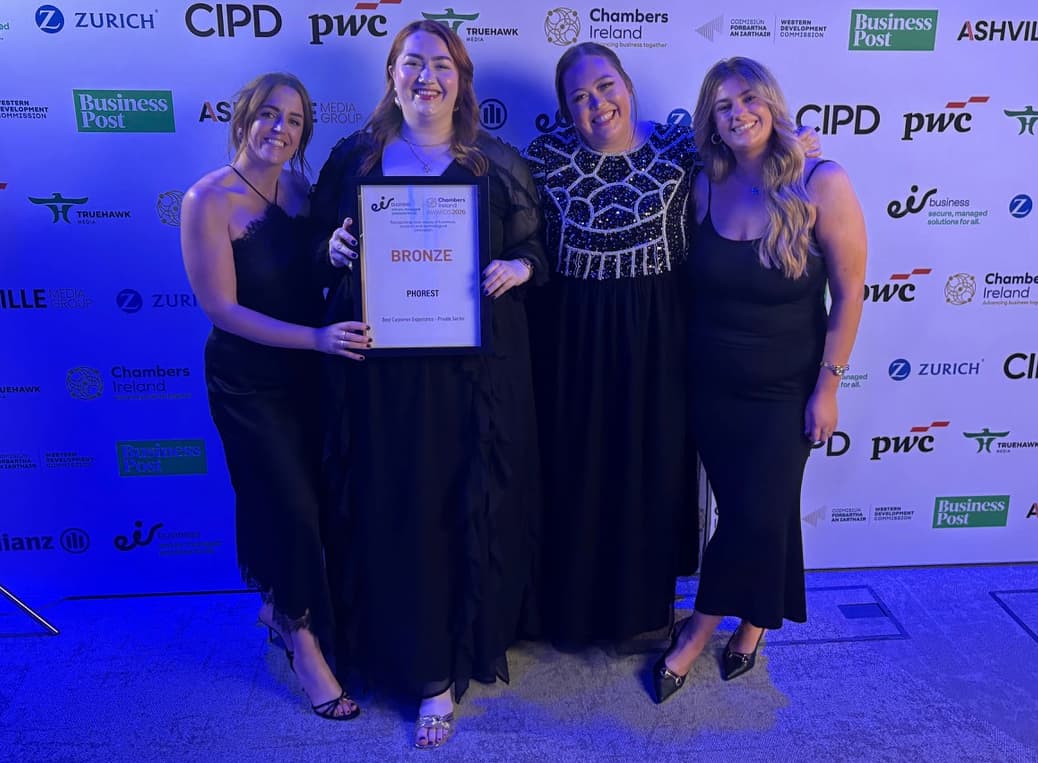 Some of the team from Phorest Salon software smile for the camera holding an award against a sponsorship board.