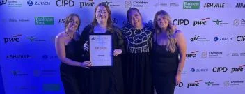 Some of the team from Phorest Salon software smile for the camera holding an award against a sponsorship board.
