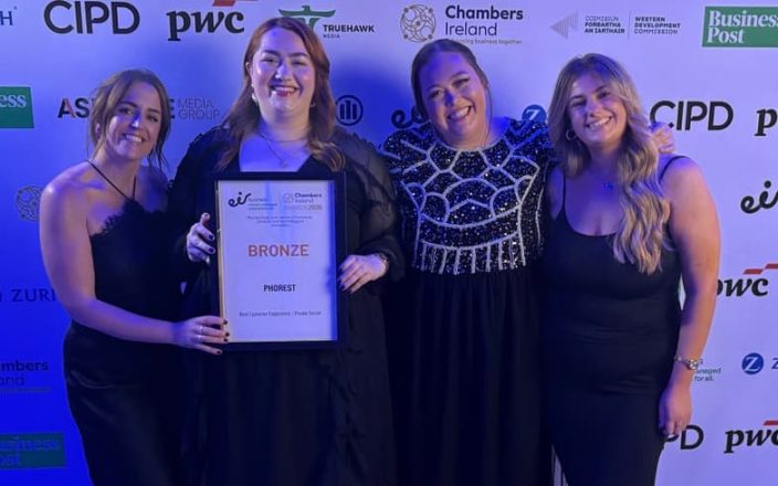 Some of the team from Phorest Salon software smile for the camera holding an award against a sponsorship board.