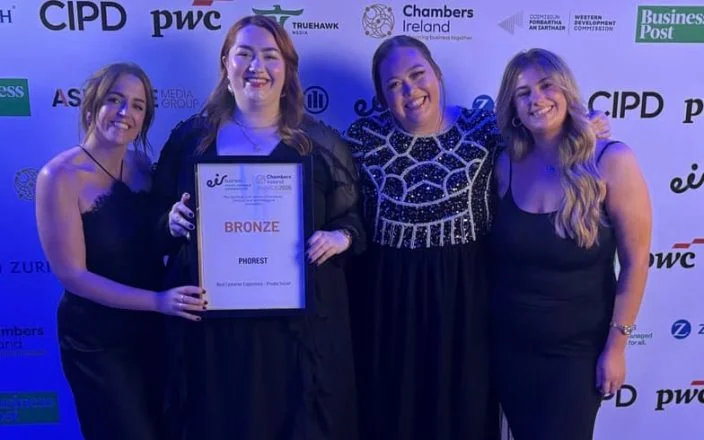 Some of the team from Phorest Salon software smile for the camera holding an award against a sponsorship board.