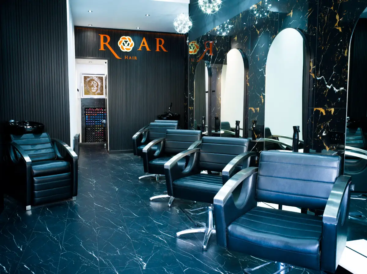 ROAR Hair & Beauty salon interior with black styling stations, marble-effect walls and contemporary luxury décor.