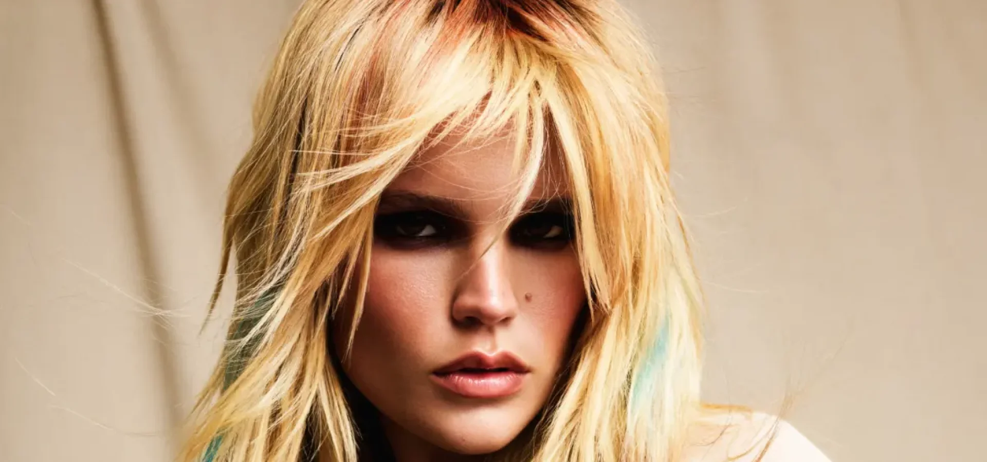 Model with long blonde layered hair, soft curtain fringe and subtle pastel highlights, showcasing a 2026 festival hairstyle.