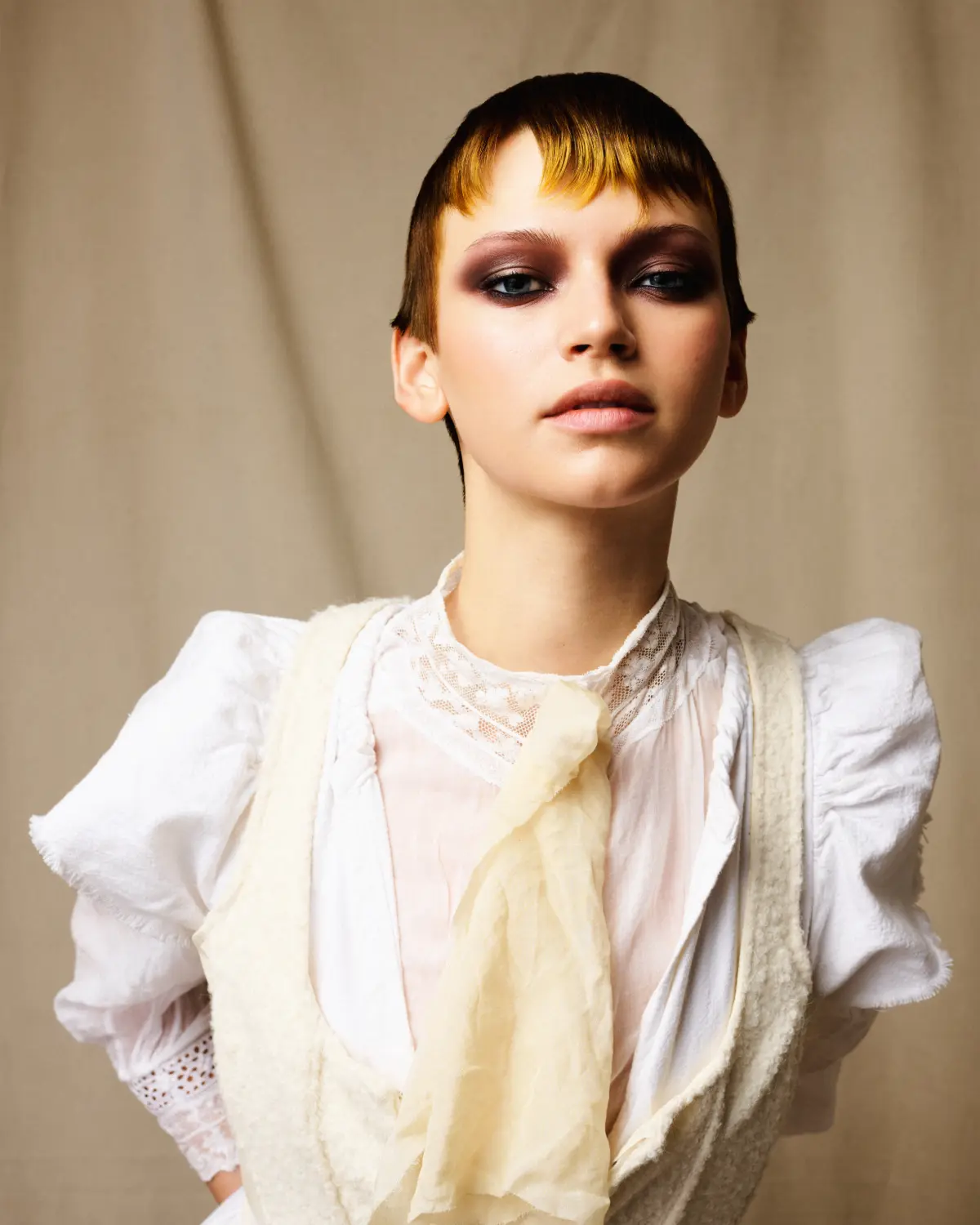 Model with cropped brunette hairstyle and golden fringe colour, showcasing Rainbow Room International's 2026 festival hair trend.