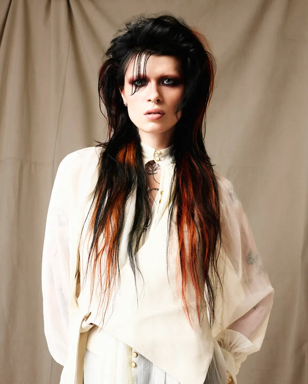 Model with long black hair and copper highlights, showcasing a voluminous festival hairstyle for 2026.