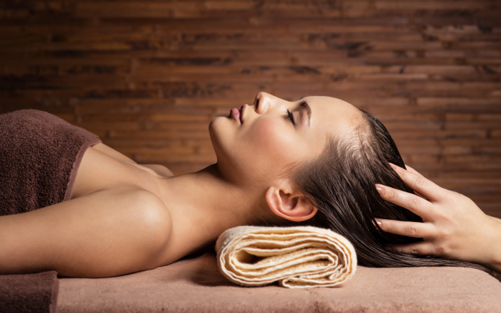 Client enjoying a relaxing head massage at a salon backwash during a luxury hair treatment focused on wellbeing.